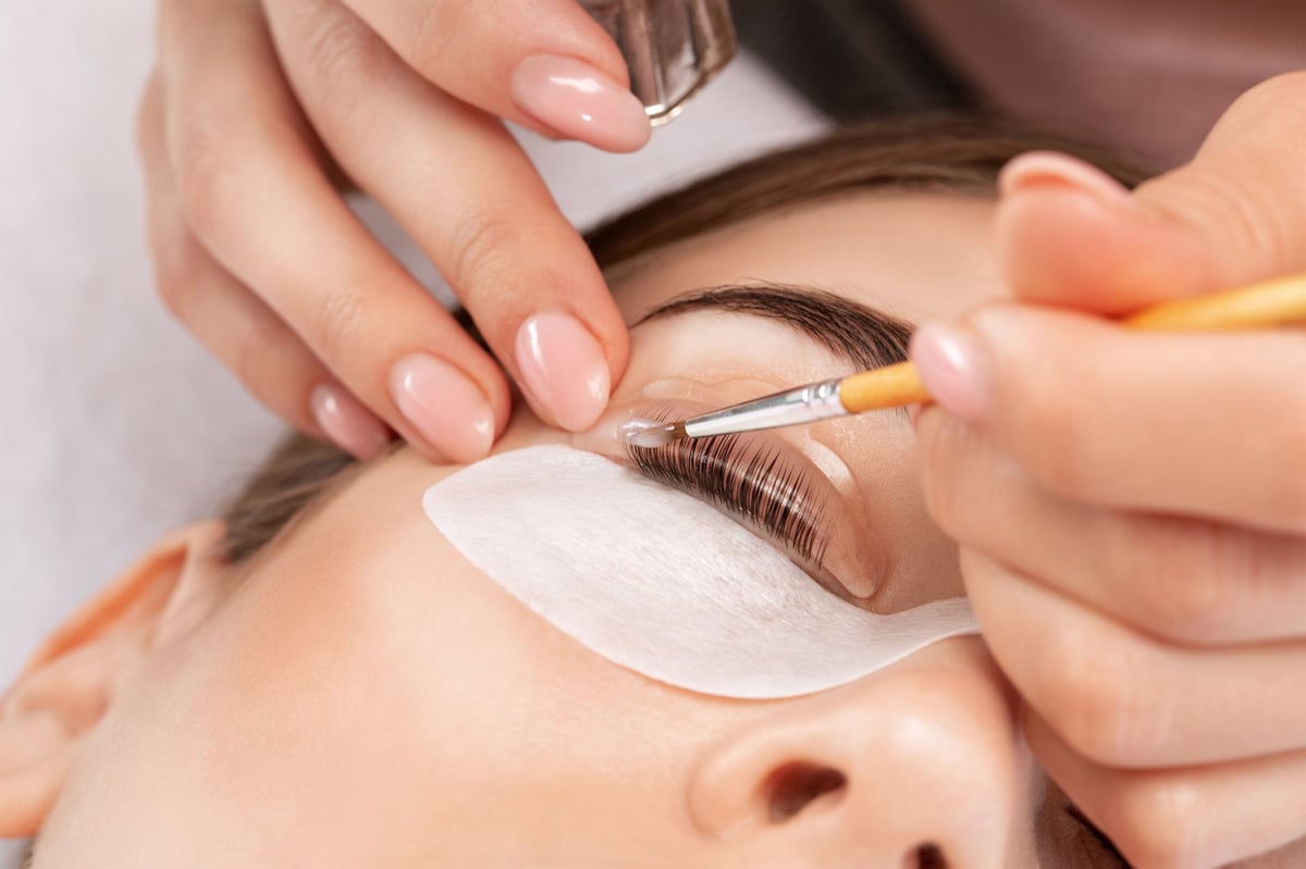 Make-up artist makes the procedure of lamination and dyeing of eyelashes to a beautiful woman in a beauty salon