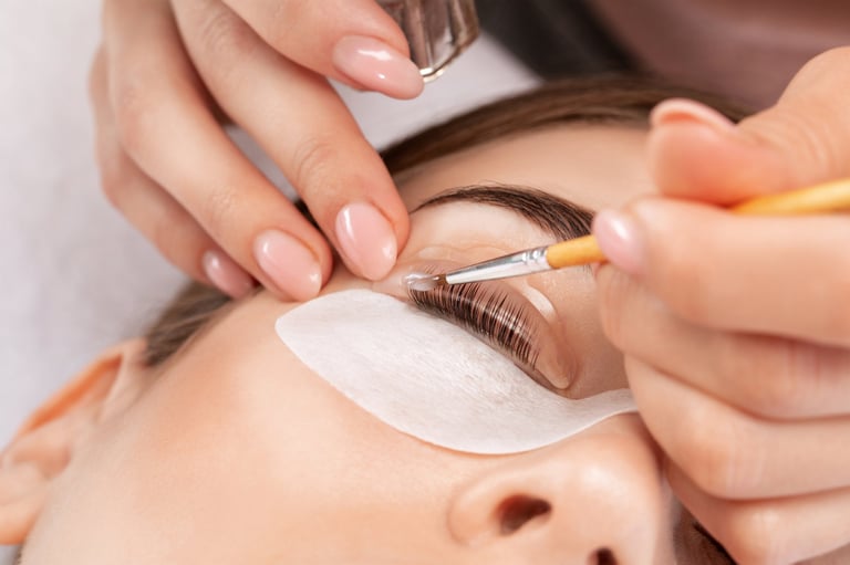 Make-up artist makes the procedure of lamination and dyeing of eyelashes to a beautiful woman in a beauty salon