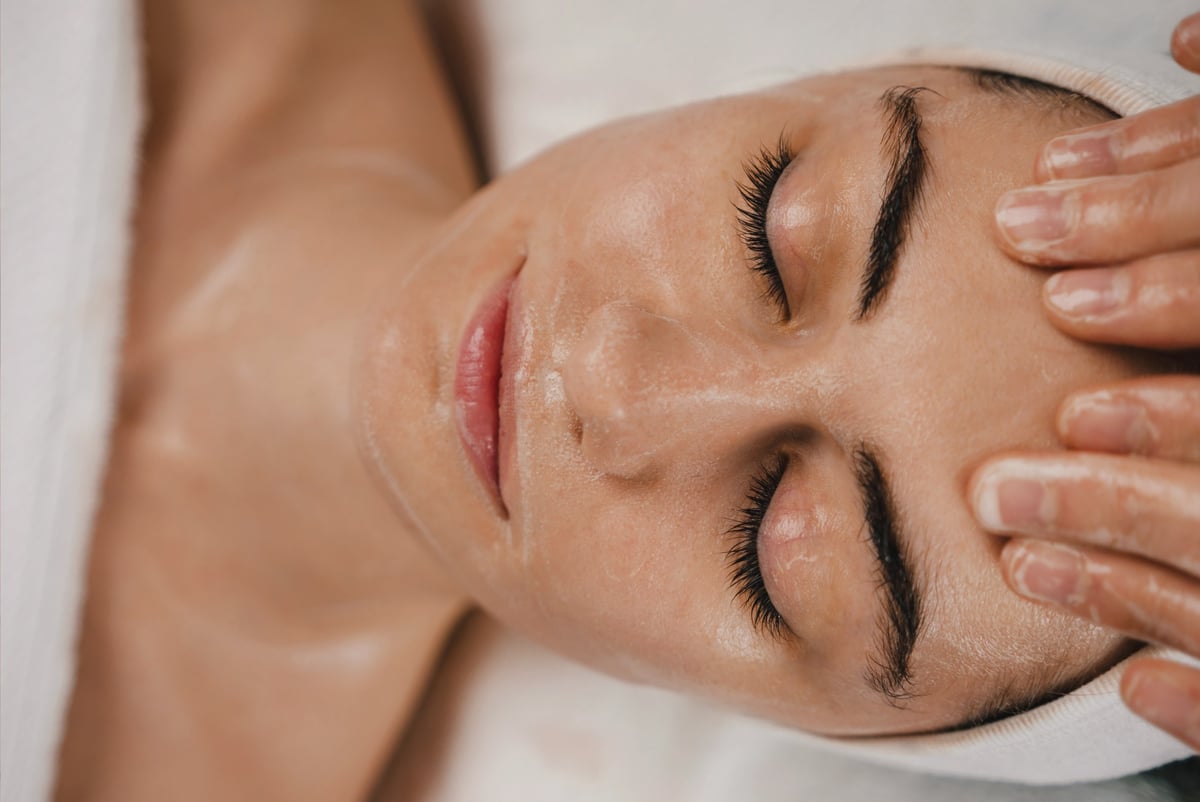 Beautiful young woman enjoying face massage at the beauty salon