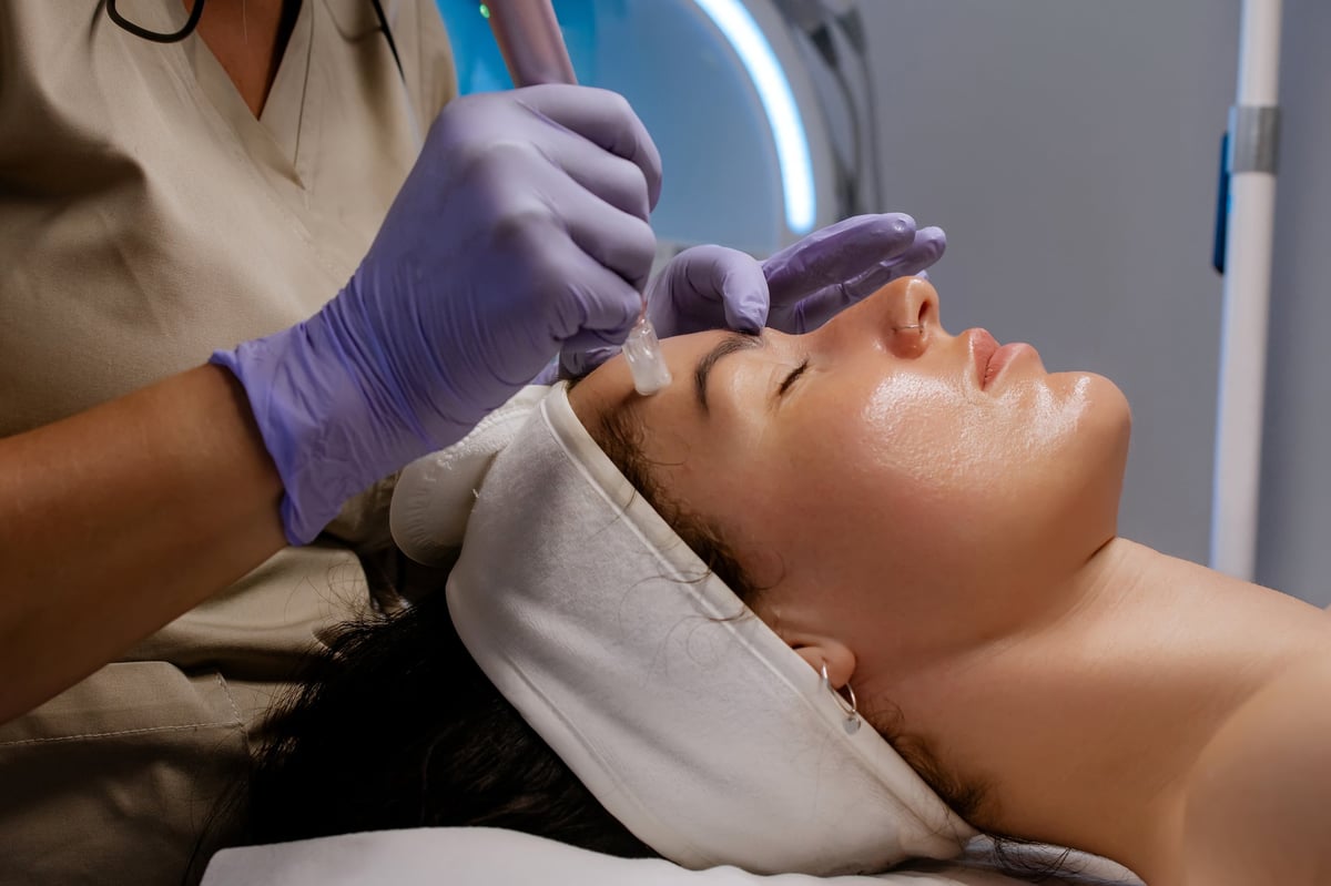 Woman receiving a professional microneedling treatment at a cosmetology clinic